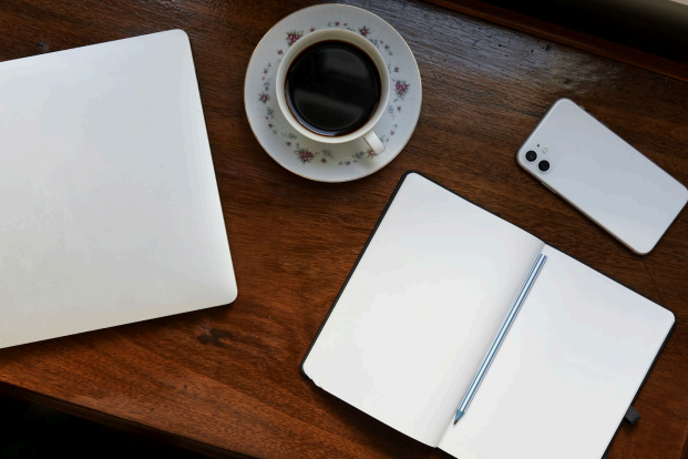 Desk with coffee, notepad, phone and laptop
