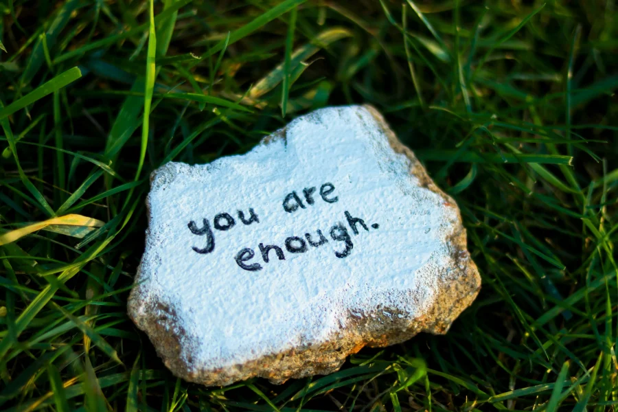 You are enough written on a rock in the grass